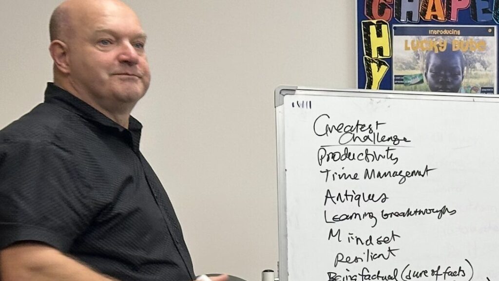 Rob Woolley standing by the whiteboard jotting down answers to a business topic